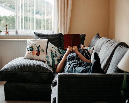 person reading a book in a comfortable room by the window